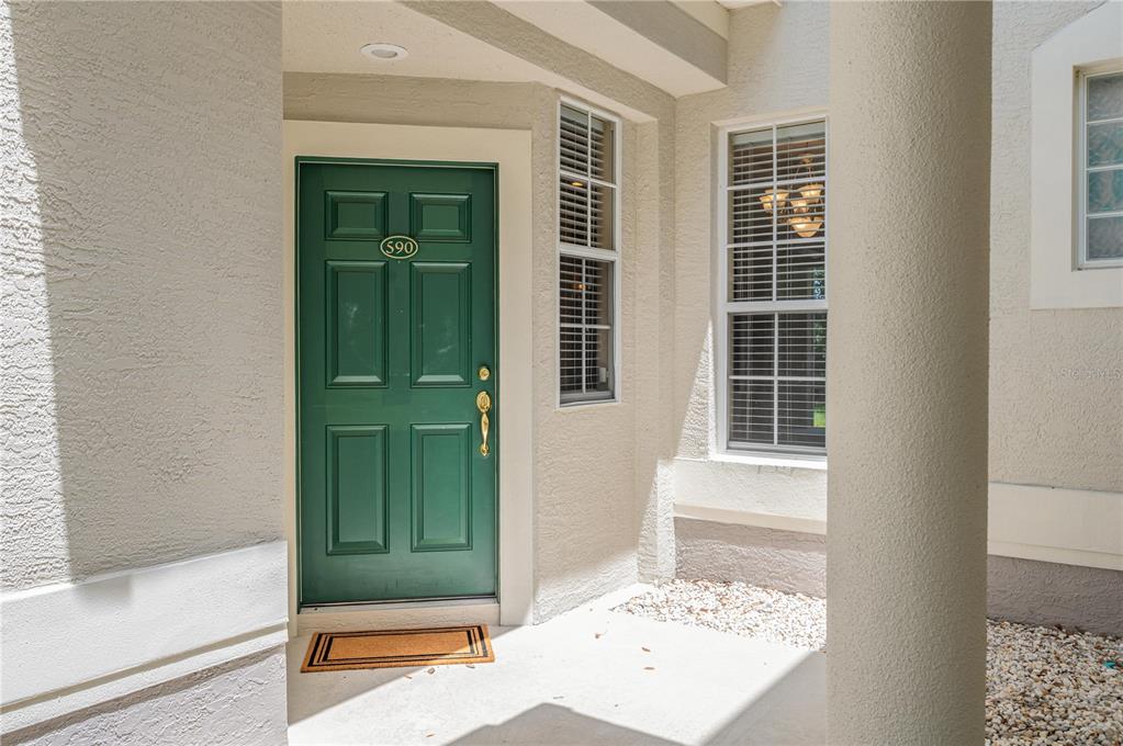 A green front door with the number 590 is set in a beige stucco entryway — 590 GRASSLANDS VILLAGE CIRCLE UNIT 590, LAKELAND, FL