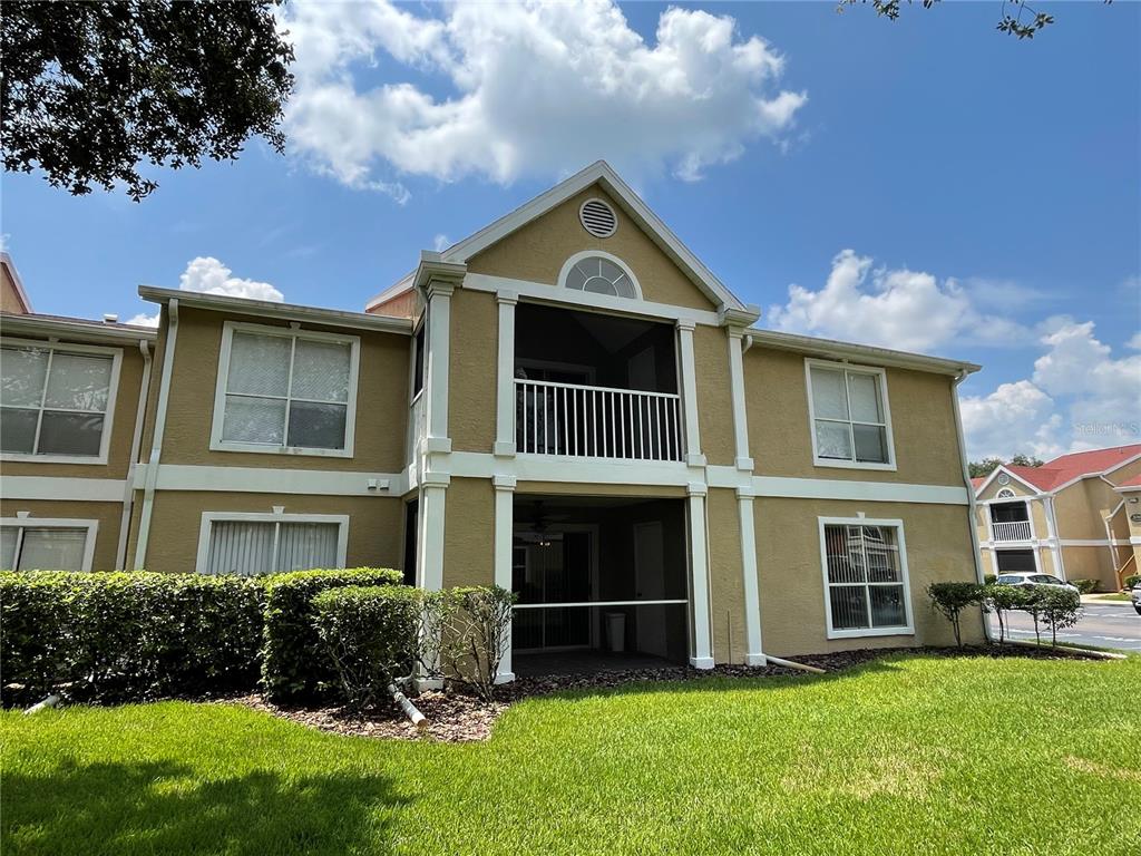 A two-story tan apartment building features a screened balcony and a ground-level patio — 9481 HIGHLAND OAK DRIVE UNIT 1402, TAMPA, FL