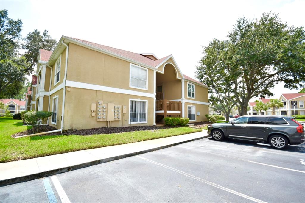 A two-story tan apartment building with a parking lot and a gray SUV — 9481 HIGHLAND OAK DRIVE UNIT 1402, TAMPA, FL