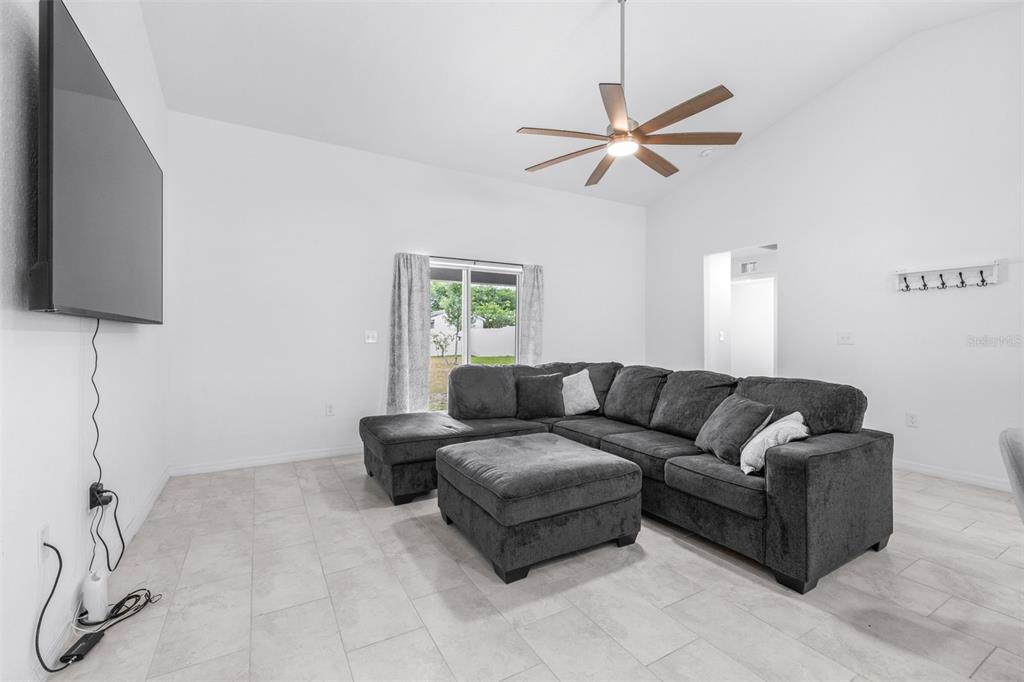 A living room features a large gray sectional sofa, tile flooring, and a wall-mounted television — 2118 HADLEY RD, BARTOW, FL