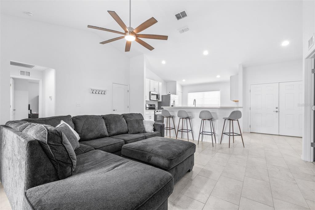A living room with a large gray sectional sofa, ceiling fan, and open kitchen area — 2118 HADLEY RD, BARTOW, FL