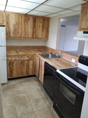 A kitchen features wood cabinets, laminate countertops, a stainless steel sink, and black appliances — 10425 SW 112th Ave # 211, Miami FL 33176, MIAMI, FL