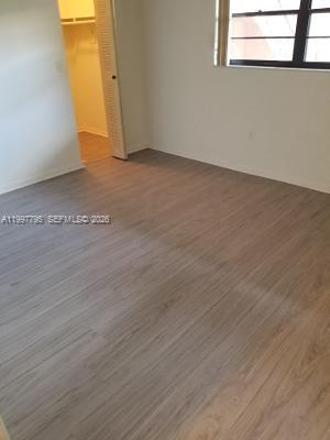 An empty bedroom features light wood-look flooring, white walls, and an open closet door — 10425 SW 112th Ave # 211, Miami FL 33176, MIAMI, FL