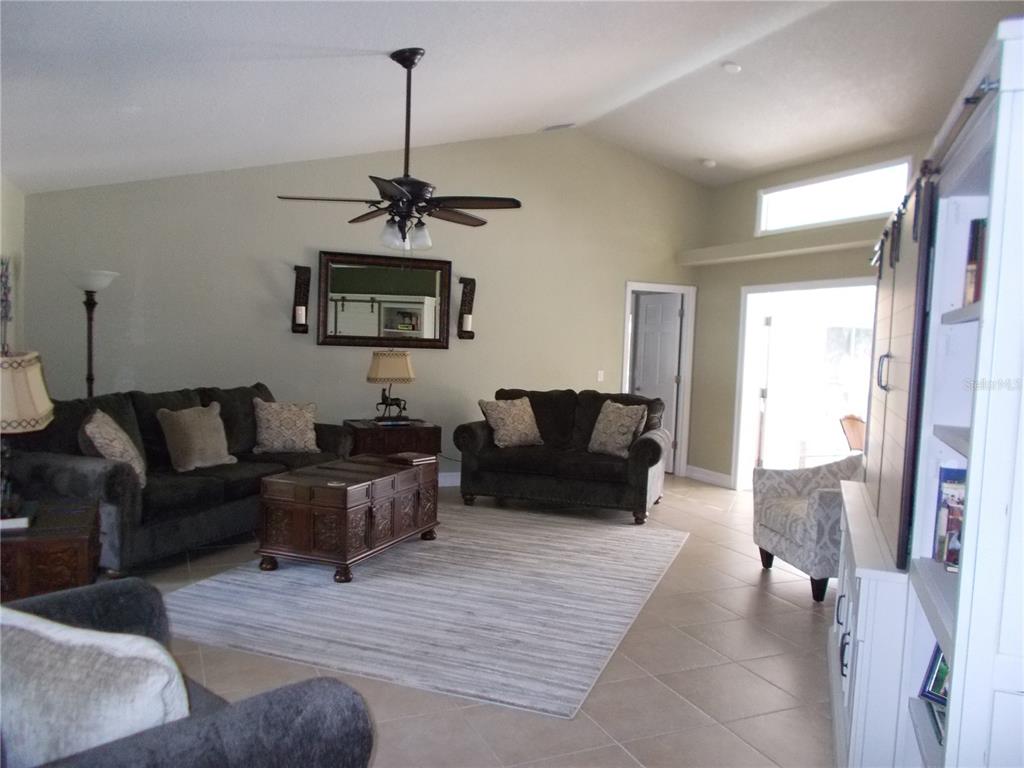 A living room features dark sofas, a wooden coffee table, and a ceiling fan — 6960 MALTON STREET, NORTH PORT, FL