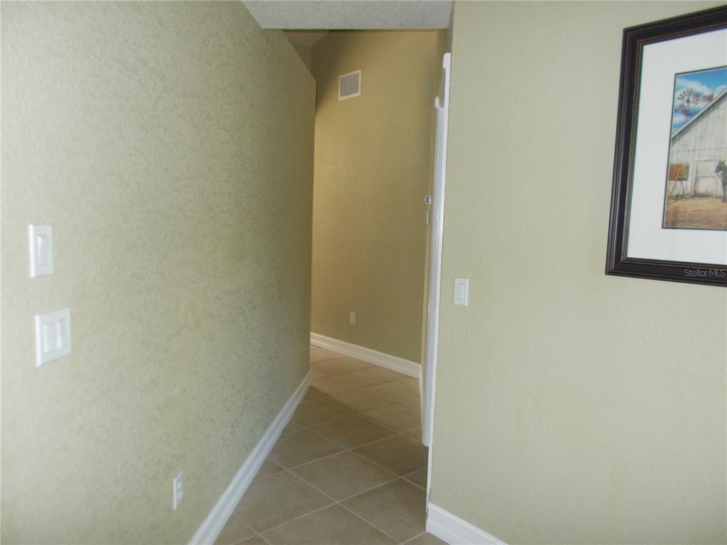 A hallway with light green walls, tiled flooring, and a framed picture on the wall — 6960 MALTON STREET, NORTH PORT, FL