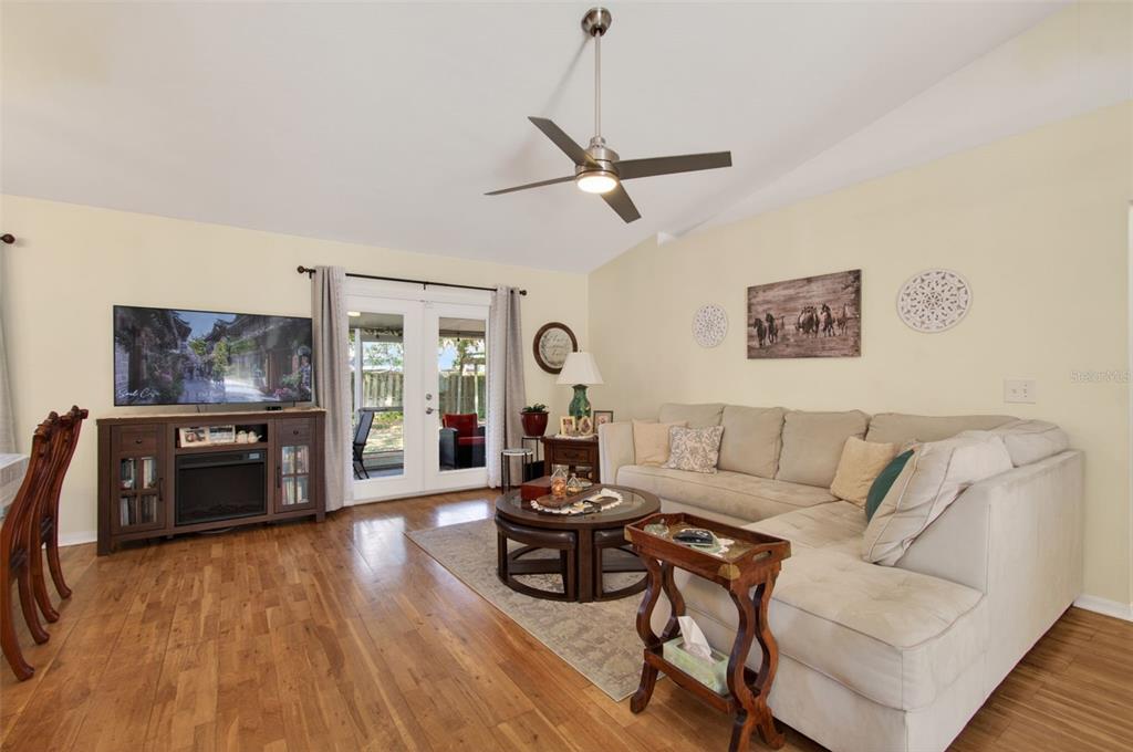 A living room with hardwood floors, a sectional sofa, a ceiling fan, and glass doors — 6146 NW 38TH TERRACE, GAINESVILLE, FL