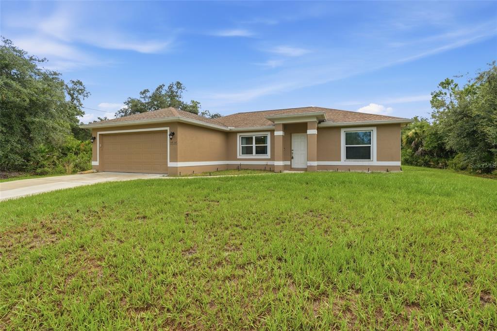 A single-story tan house with a two-car garage and a front lawn — 3535 SHAWNEE TERRACE, NORTH PORT, FL