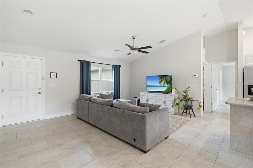 A living room features a gray sectional sofa, a television on a white console, and tile flooring — 3535 SHAWNEE TERRACE, NORTH PORT, FL