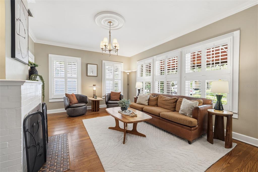 A living room features a fireplace, a brown sofa, two armchairs, and plantation shutters — 912 S FREMONT AVENUE, TAMPA, FL