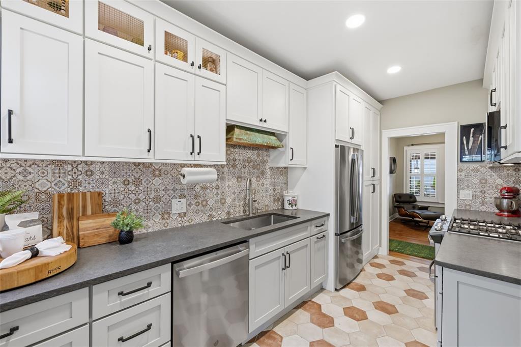 A kitchen features white cabinets, dark countertops, patterned tile backsplashes, and hexagonal floor tiles — 912 S FREMONT AVENUE, TAMPA, FL