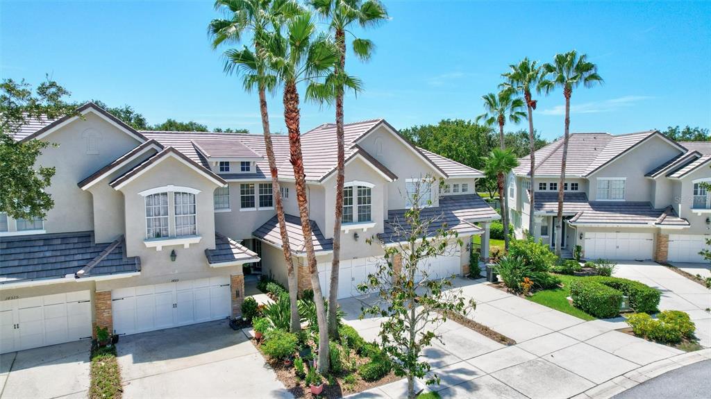 A two-story townhouse with a beige stucco exterior, two garage doors, and a tiled roof — 14511 MIRABELLE VISTA CIRCLE, TAMPA, FL