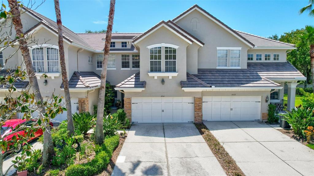 The exterior of a two-story house features a stone-accented garage, a walkway, and landscaping — 14511 MIRABELLE VISTA CIRCLE, TAMPA, FL
