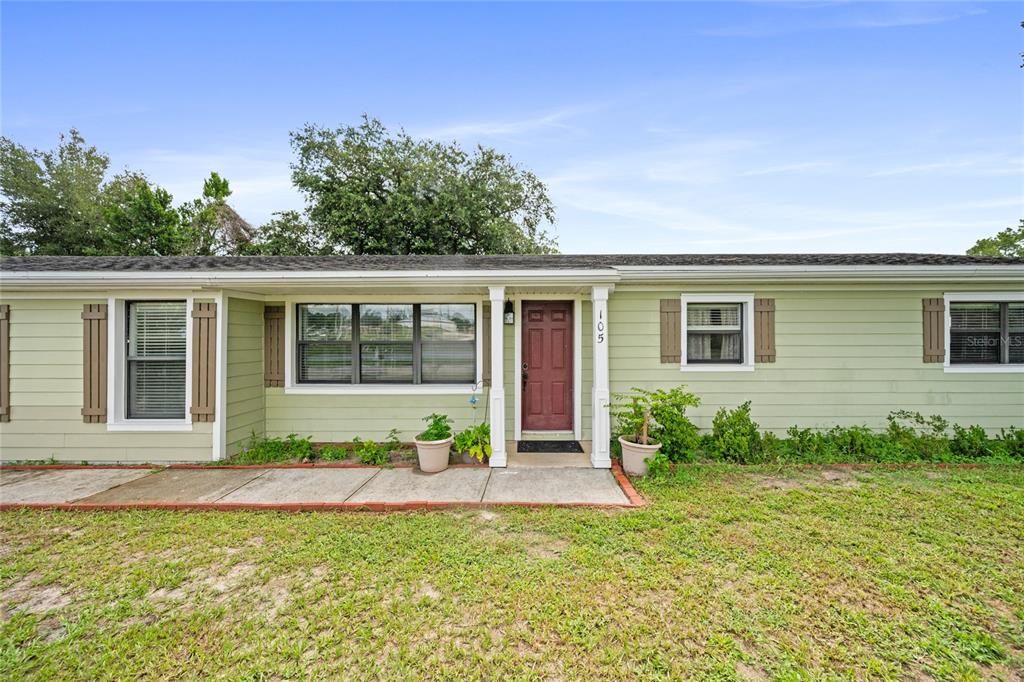 A single-story house with light green siding, a red front door, and a concrete walkway — 105 MIRROR DRIVE, SANFORD, FL