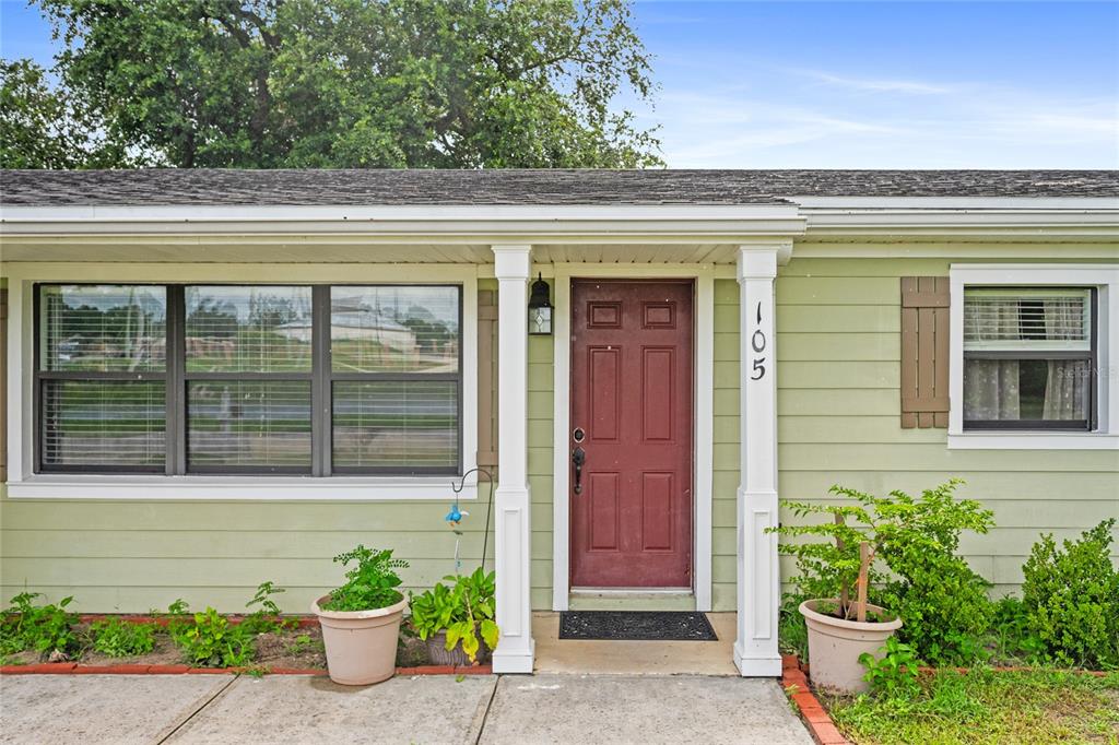 A light green house exterior features a red front door with house number 105 — 105 MIRROR DRIVE, SANFORD, FL