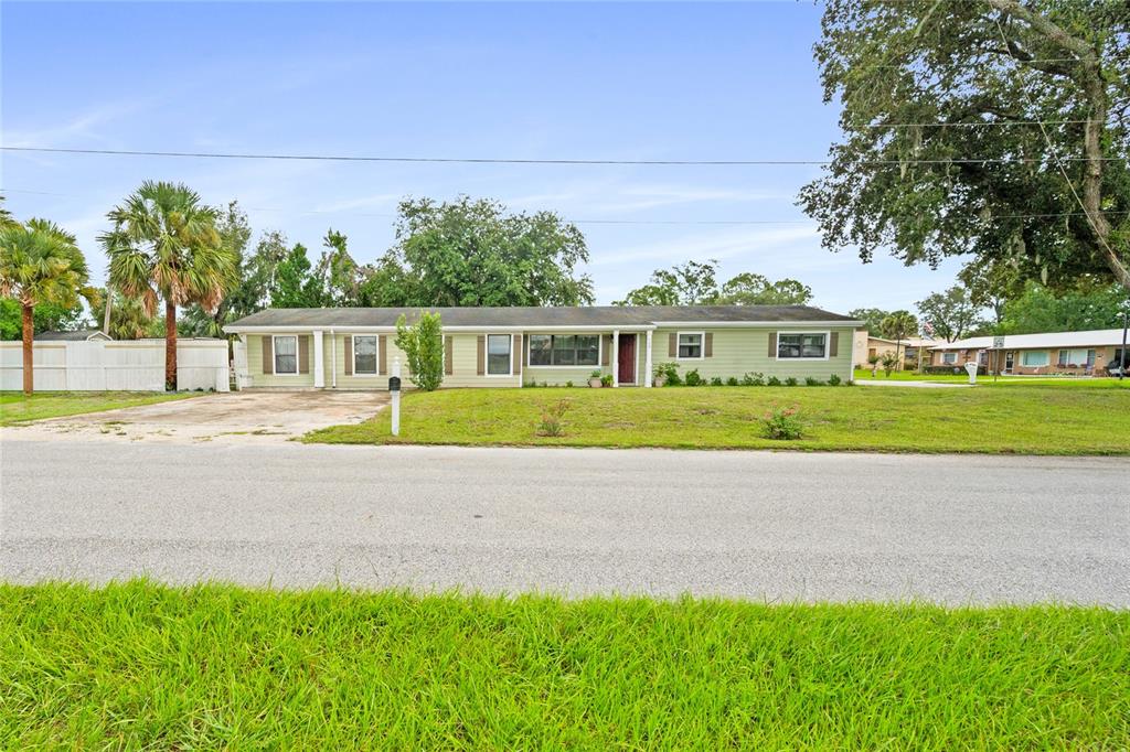 A single-story, light green house with a flat roof sits behind a grassy front yard — 105 MIRROR DRIVE, SANFORD, FL