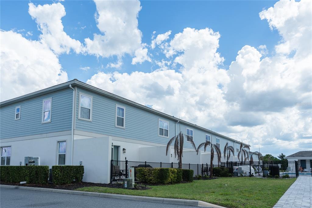 A multi-unit residential building with light blue siding, white stucco walls, and a fenced backyard — 7901 PUTTING WAY, KISSIMMEE, FL
