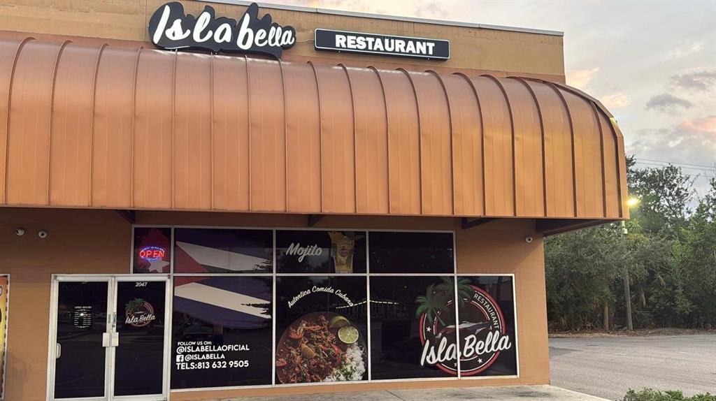 The exterior of a Cuban restaurant features a large copper-colored awning and glass storefront windows — 2047 E FOWLER, TAMPA, FL