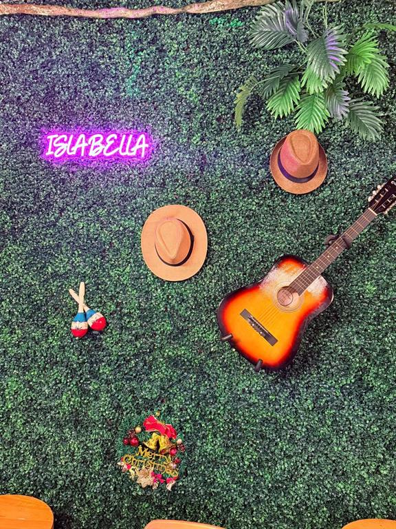 A green wall backdrop features a neon sign, two hats, a guitar, and maracas — 2047 E FOWLER, TAMPA, FL