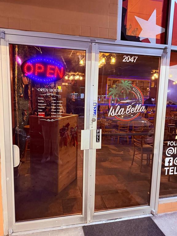 The glass double doors of a restaurant entrance feature an open sign and business hours — 2047 E FOWLER, TAMPA, FL