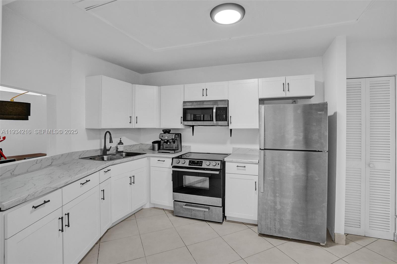 A kitchen features white cabinets, stainless steel appliances, and light-colored countertops — 1780 NE 191st St # 2, Miami FL 33179, MIAMI, FL