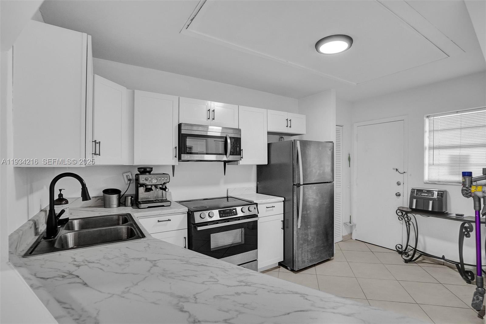 A kitchen features white cabinets, stainless steel appliances, and marble-patterned countertops — 1780 NE 191st St # 2, Miami FL 33179, MIAMI, FL