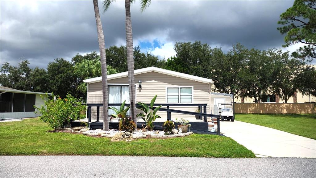 A single-story manufactured home with a front deck, palm trees, and a concrete driveway — 2100 KINGS HIGHWAY UNIT 956A, PORT CHARLOTTE, FL