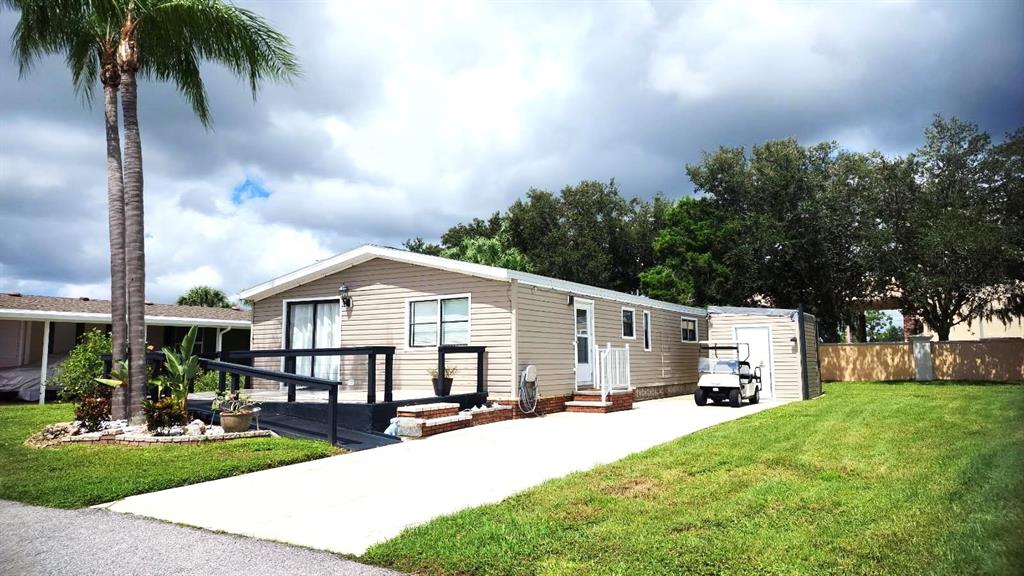 A single-story manufactured home with a concrete driveway, a small deck, and a golf cart — 2100 KINGS HIGHWAY UNIT 956A, PORT CHARLOTTE, FL