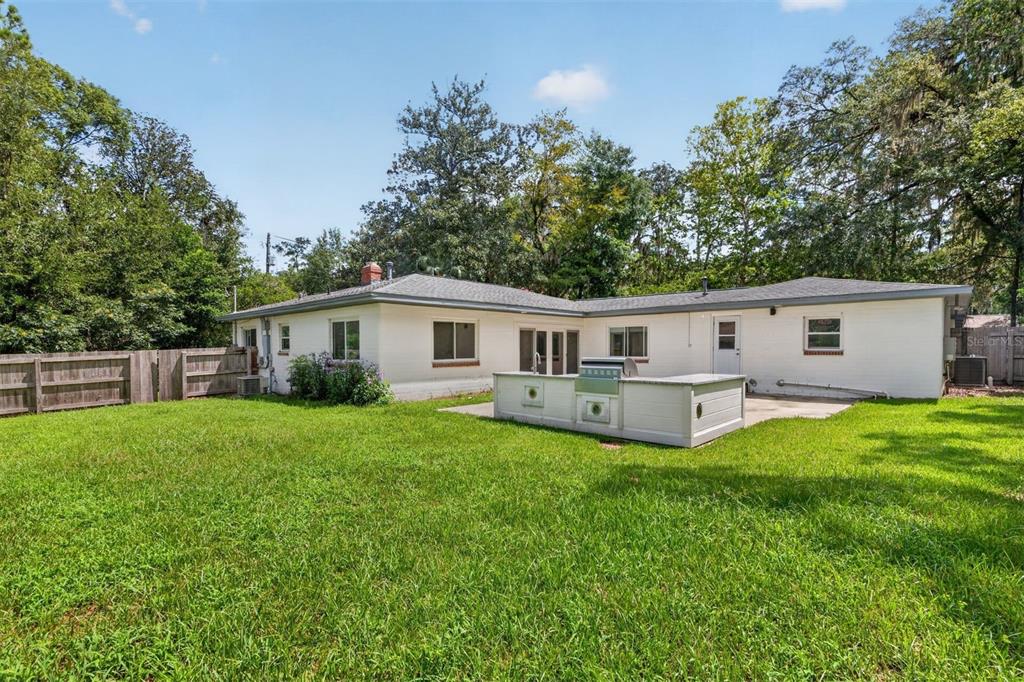 A white brick house with an outdoor kitchen on a concrete patio in the backyard — 2707 NW 4TH AVENUE, GAINESVILLE, FL