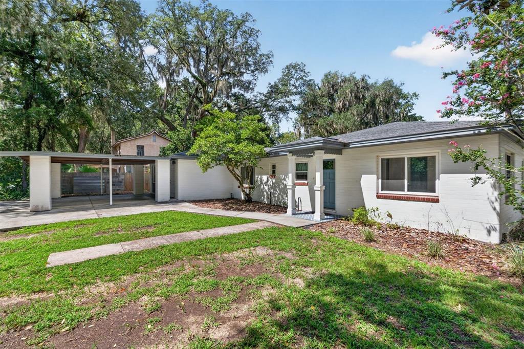 A white brick single-story house with a carport and a front yard with trees — 2707 NW 4TH AVENUE, GAINESVILLE, FL