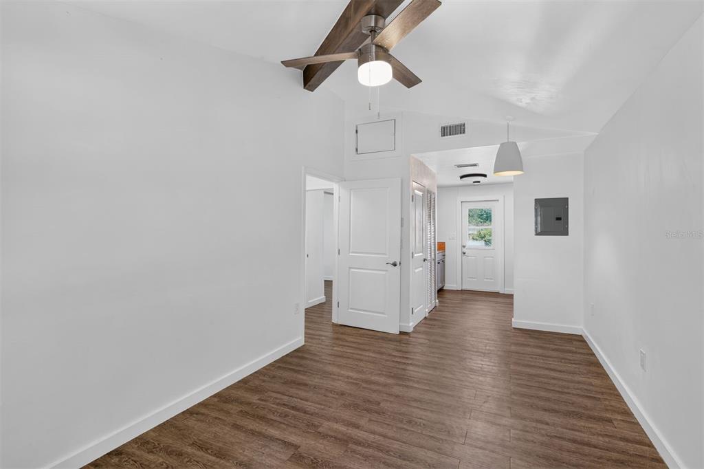 A room with wood-look flooring, a vaulted ceiling with a fan, and a white door — 2707 NW 4TH AVENUE, GAINESVILLE, FL