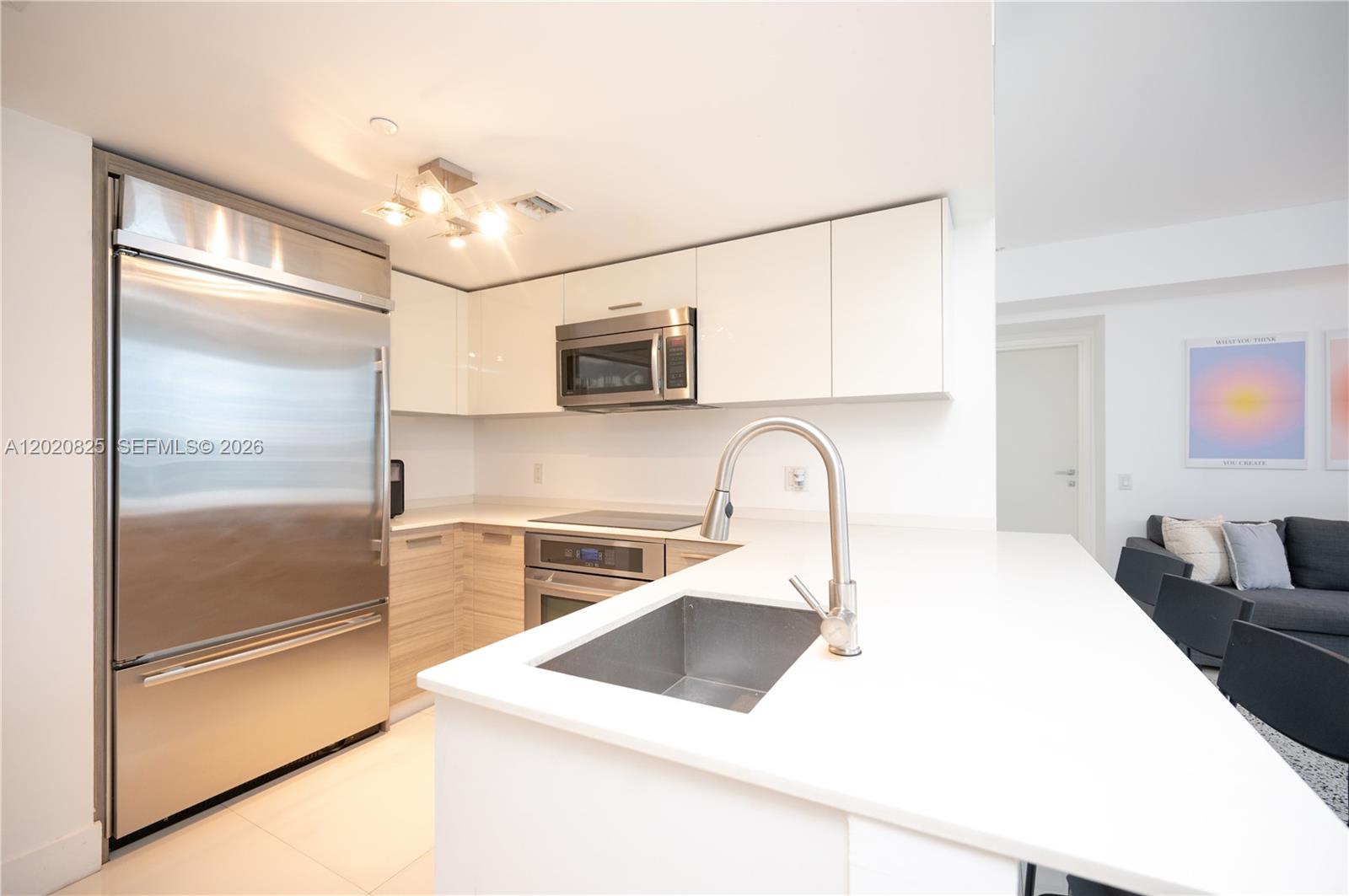 A modern kitchen features white cabinetry, stainless steel appliances, and a white quartz countertop — 1300 Brickell Bay Dr # 1601, Miami FL 33131, MIAMI, FL