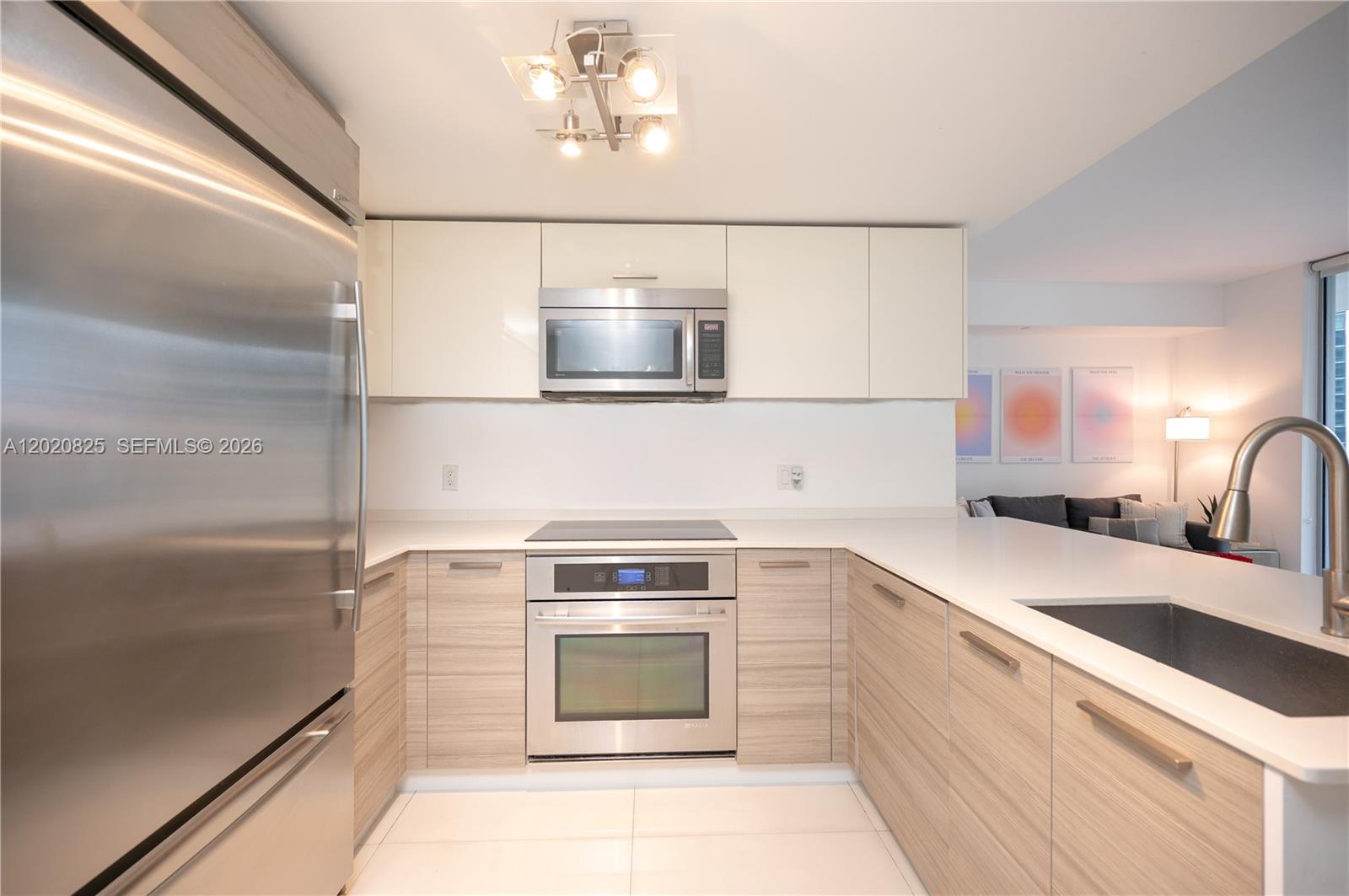 A modern kitchen features stainless steel appliances, light wood cabinetry, and white countertops — 1300 Brickell Bay Dr # 1601, Miami FL 33131, MIAMI, FL