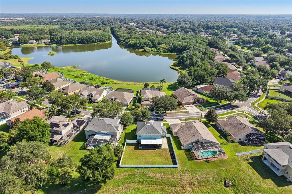 An aerial view shows a residential neighborhood with houses, a lake, and green spaces — 205 ROSANA DRIVE, BRANDON, FL