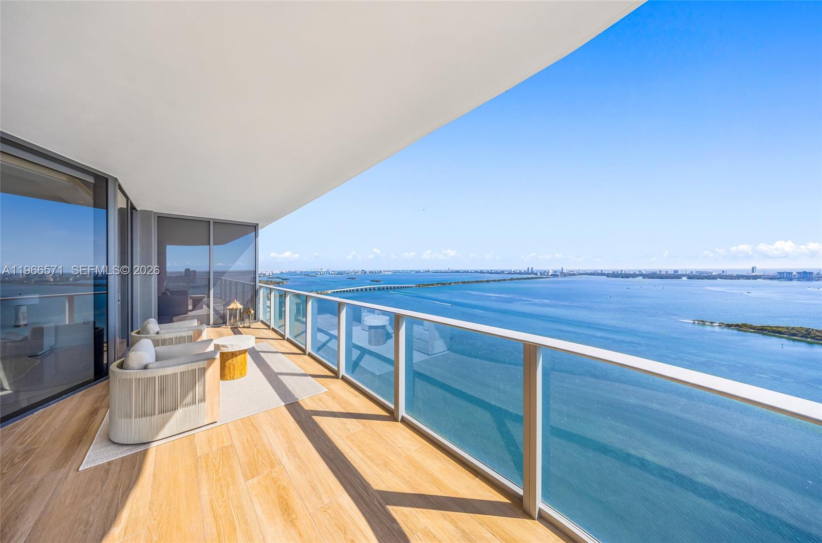 A high-rise balcony features wood-look tile flooring, glass railings, and expansive bay views — 700 NE 24th St # 4007, Miami FL 33137, MIAMI, FL