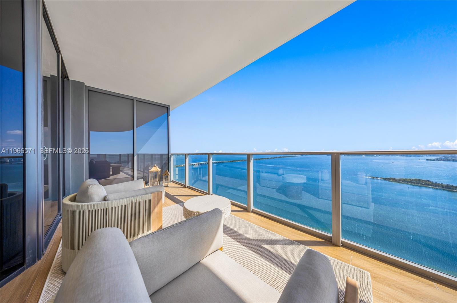 A balcony with two armchairs overlooks a large body of water under a clear sky — 700 NE 24th St # 4007, Miami FL 33137, MIAMI, FL