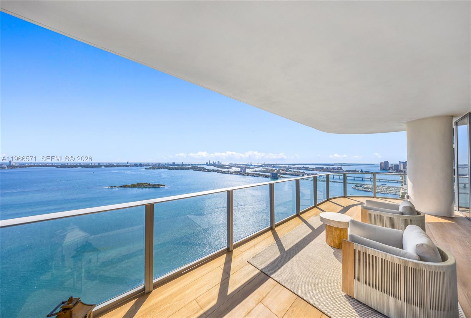 A high-rise balcony features wood flooring, glass railings, and panoramic views of the ocean — 700 NE 24th St # 4007, Miami FL 33137, MIAMI, FL