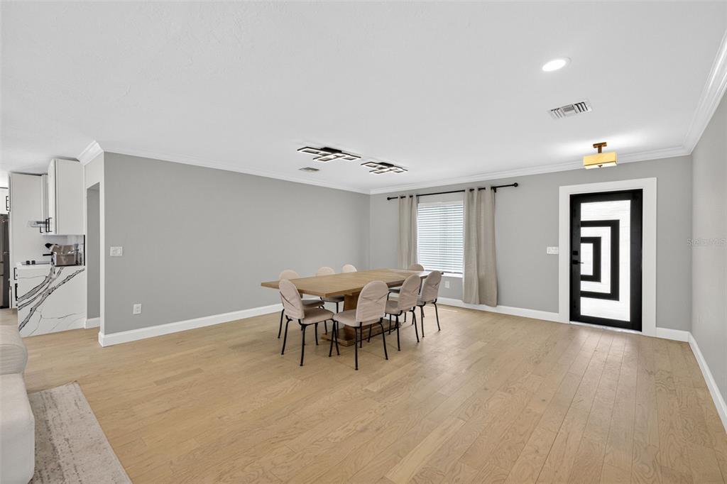 A dining room features light wood floors, a wooden table with six chairs, and gray walls — 5073 HIGEL AVENUE, SARASOTA, FL