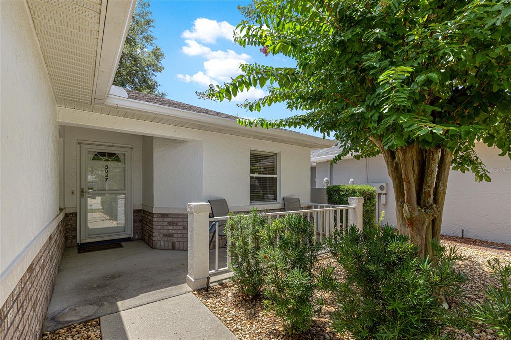 A concrete walkway leads to the front entrance of a house with a small porch — 9037 SW 91ST CIRCLE, OCALA, FL