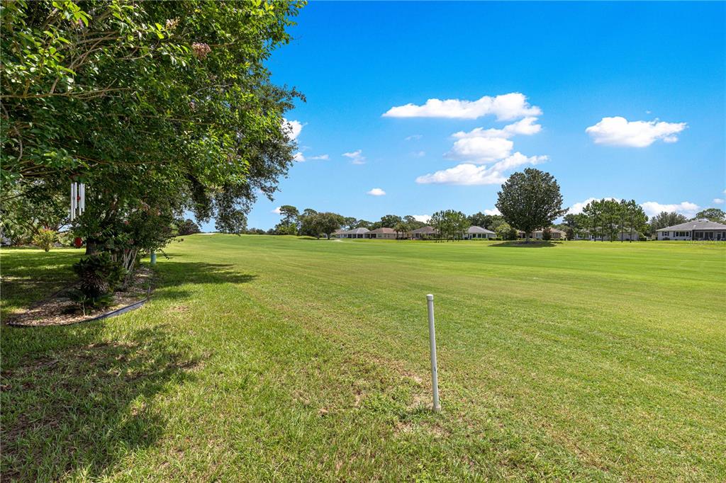 A view of a grassy golf course fairway bordered by trees and residential homes — 9037 SW 91ST CIRCLE, OCALA, FL