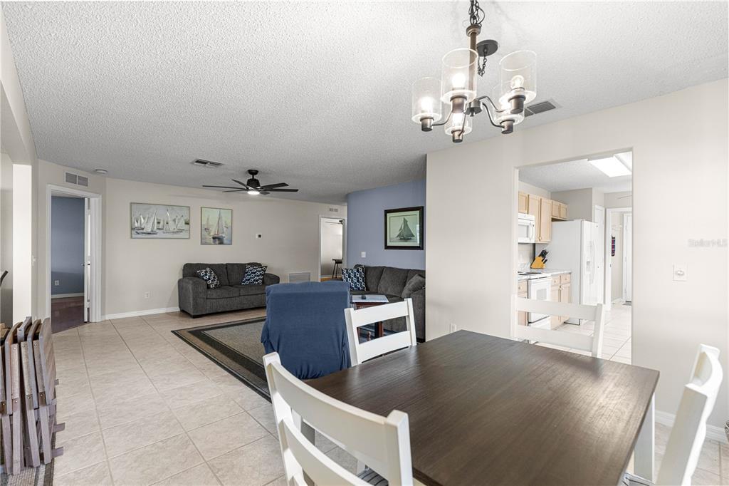 A dining area with a dark table and white chairs opens into a living room — 9037 SW 91ST CIRCLE, OCALA, FL