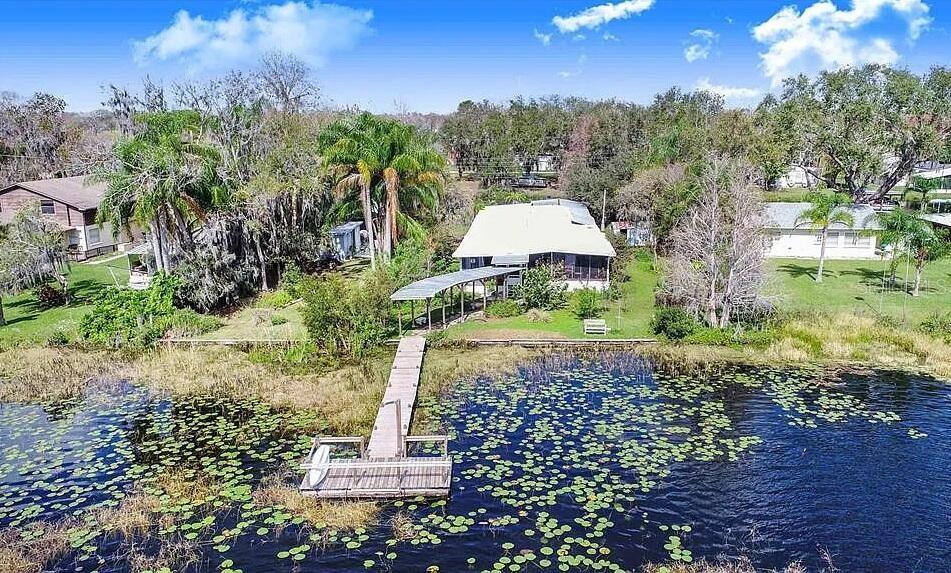 An aerial view shows a house with a dock extending into a lily-covered lake — 2360 LAKEVIEW DRIVE, HAINES CITY, FL