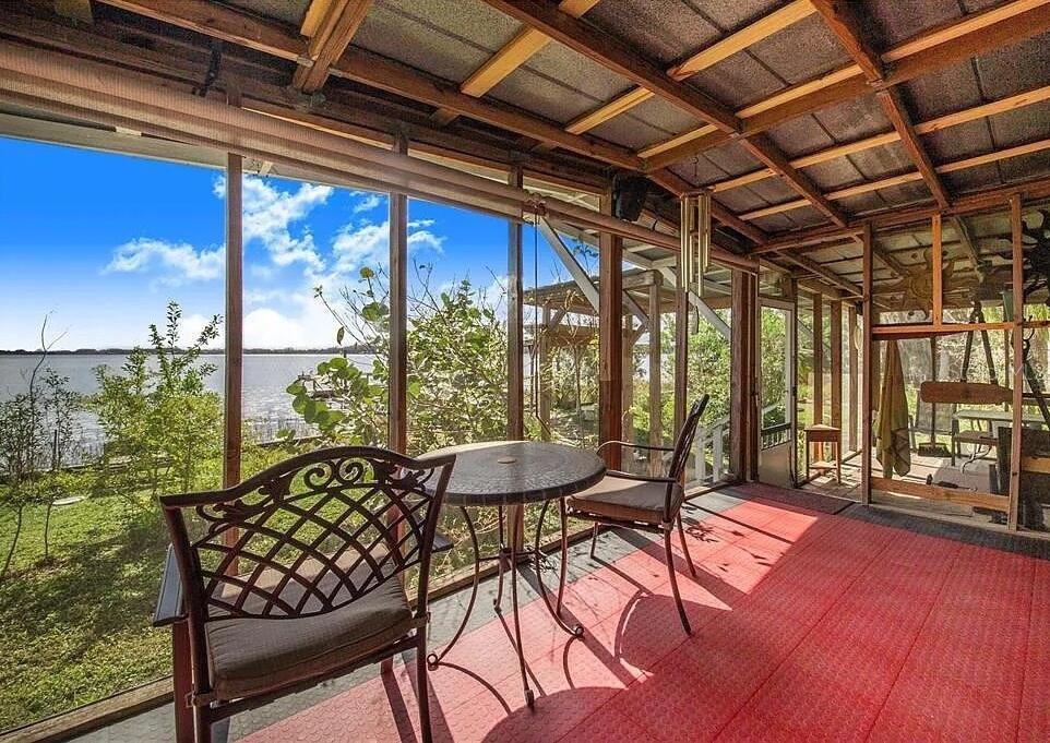 A screened-in porch with a red floor, metal furniture, and a view of the water — 2360 LAKEVIEW DRIVE, HAINES CITY, FL