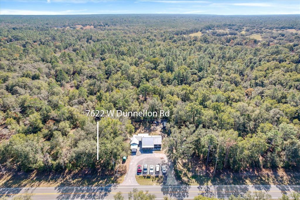 An aerial view shows a house surrounded by dense forest next to a paved road — 7622 W DUNNELLON ROAD, DUNNELLON, FL