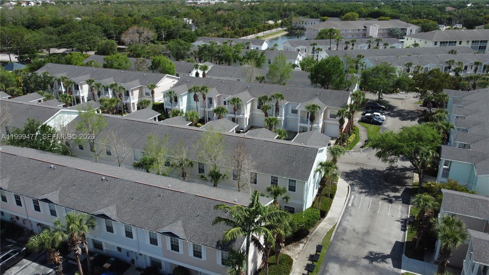 An aerial view shows multiple rows of multi-story townhomes with grey roofs and palm trees — 3304 Lisa Ln # 102, Naples FL 34109, NAPLES, FL