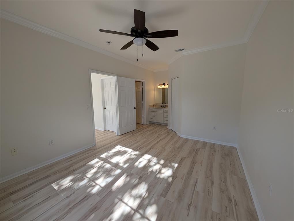 A bedroom with light wood-look flooring, a ceiling fan, and an attached bathroom vanity area — 2107 PORTOFINO PLACE UNIT 30-302, PALM HARBOR, FL