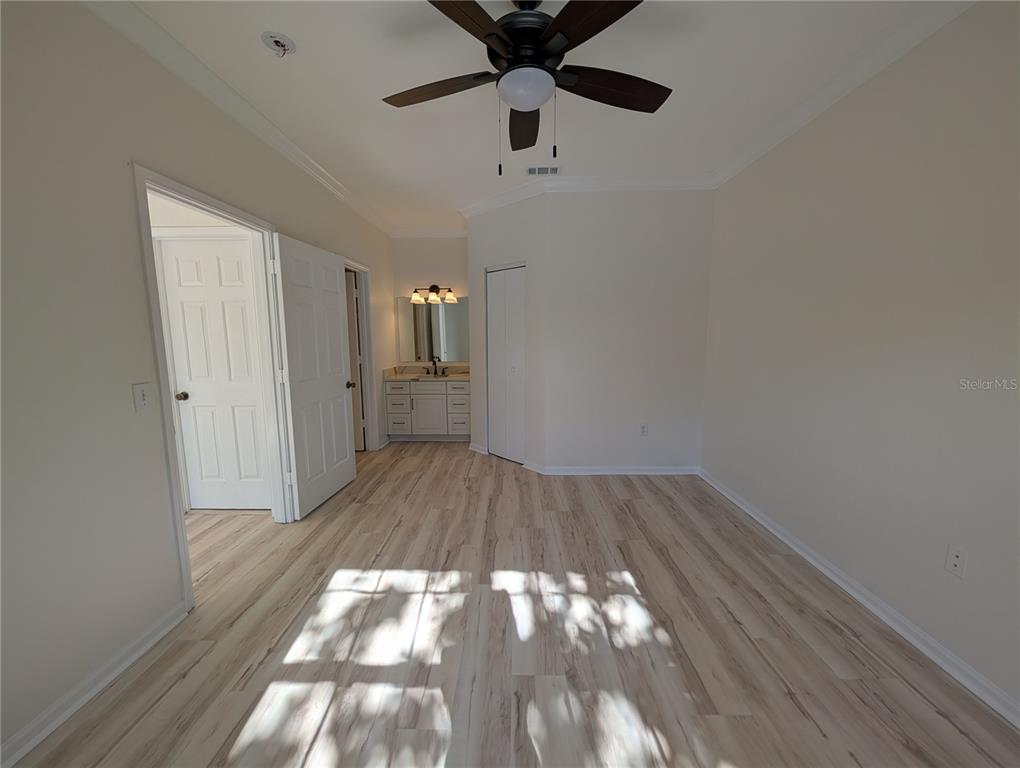A bedroom with light wood-look flooring, a ceiling fan, and an attached bathroom vanity area — 2107 PORTOFINO PLACE UNIT 30-302, PALM HARBOR, FL