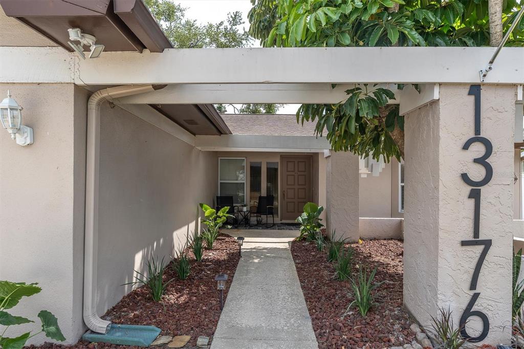 A concrete walkway leads to the front entrance of a house with a covered porch — 13176 DORCHESTER DRIVE, SEMINOLE, FL