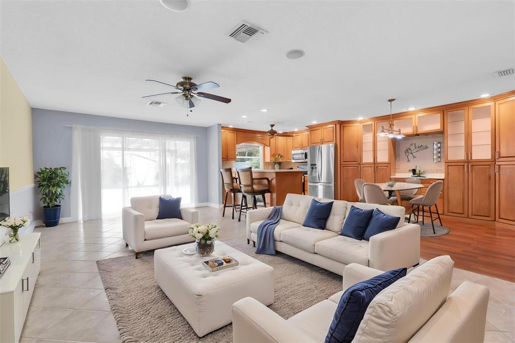 An open-concept living room and kitchen with light-colored furniture, tile flooring, and wood cabinetry — 13176 DORCHESTER DRIVE, SEMINOLE, FL