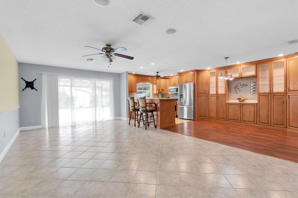 An open-concept kitchen and living area features tile flooring, wood cabinetry, and a center island — 13176 DORCHESTER DRIVE, SEMINOLE, FL