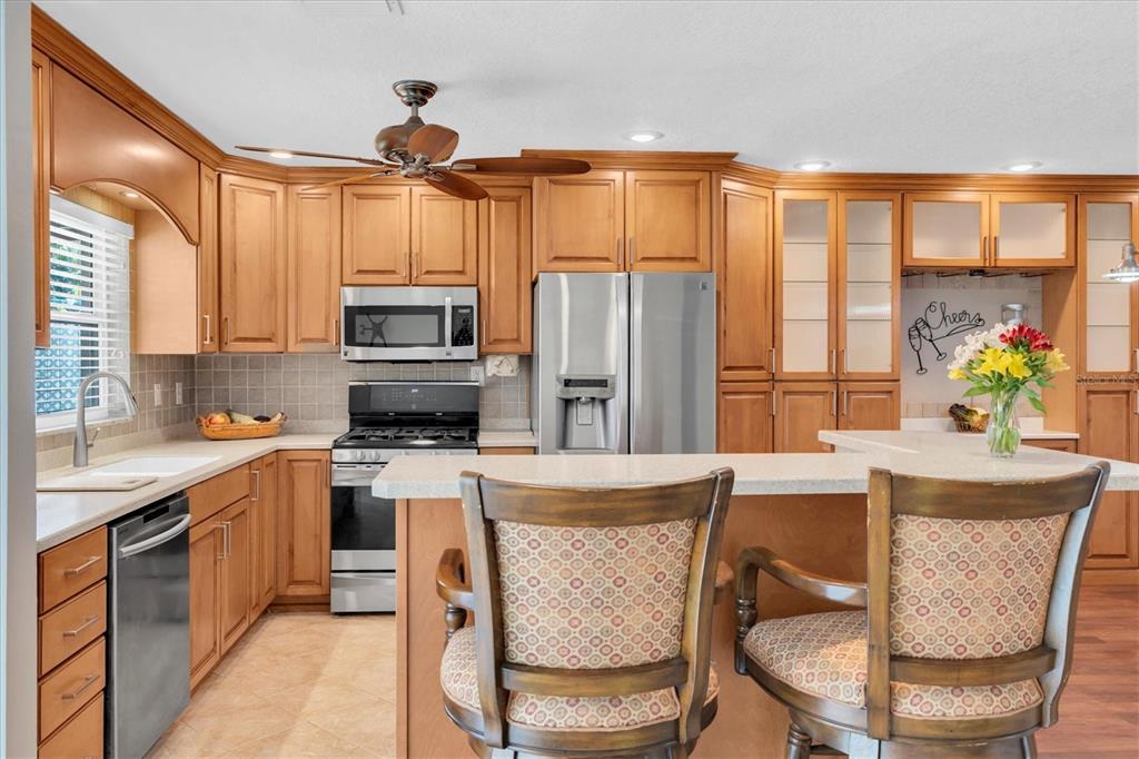 A kitchen features light wood cabinets, stainless steel appliances, a breakfast bar, and two chairs — 13176 DORCHESTER DRIVE, SEMINOLE, FL